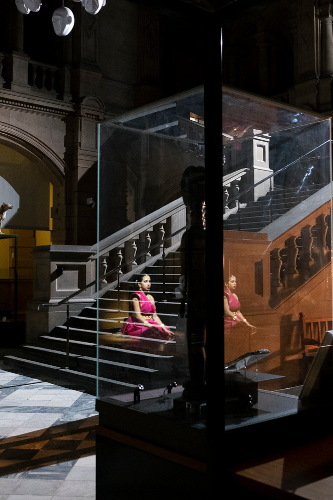 Reflection of woman sitting crossed-legged wearing a pink sari