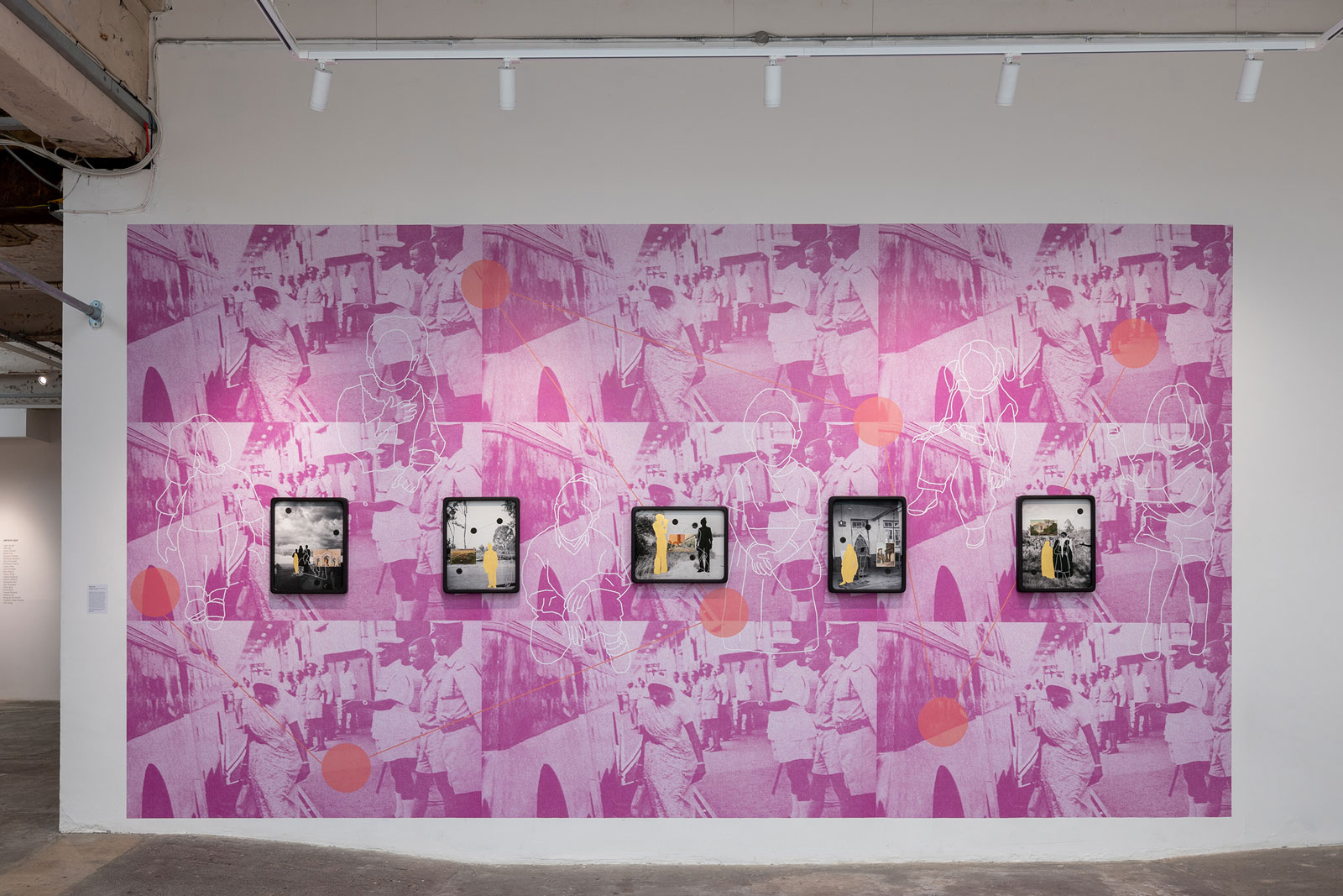 A gallery wall features five framed photographs against a pink, collage-style wallpaper with a repeating image of a women, line drawings of figures and geometric shapes.