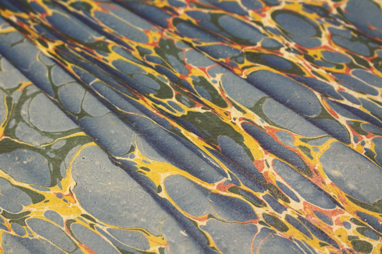 A close-up of a blue, green, red, and yellow paper-marbled surface.