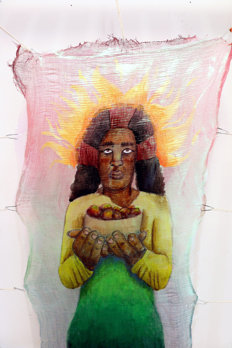 A painted fabric artwork depicting a woman holding a bowl of fruits, with a fiery, golden aura surrounding her head. The woman’s expression is calm, her hands carefully presenting the bowl.